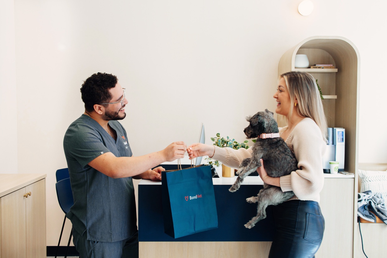 Image of a Bond Vet employee and a customer holding their dog.